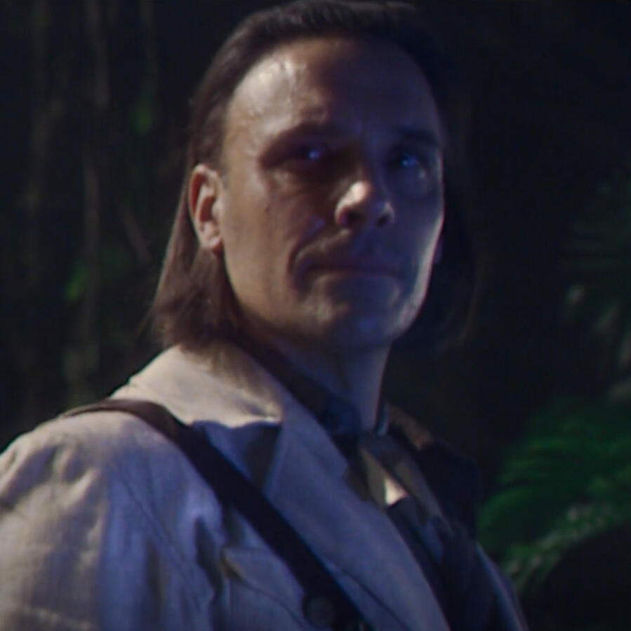 doctor steven grant from tomb buster in the moon knight show. he has straight shoulder length hair combed back and is wearing a cliché archaeologist costume